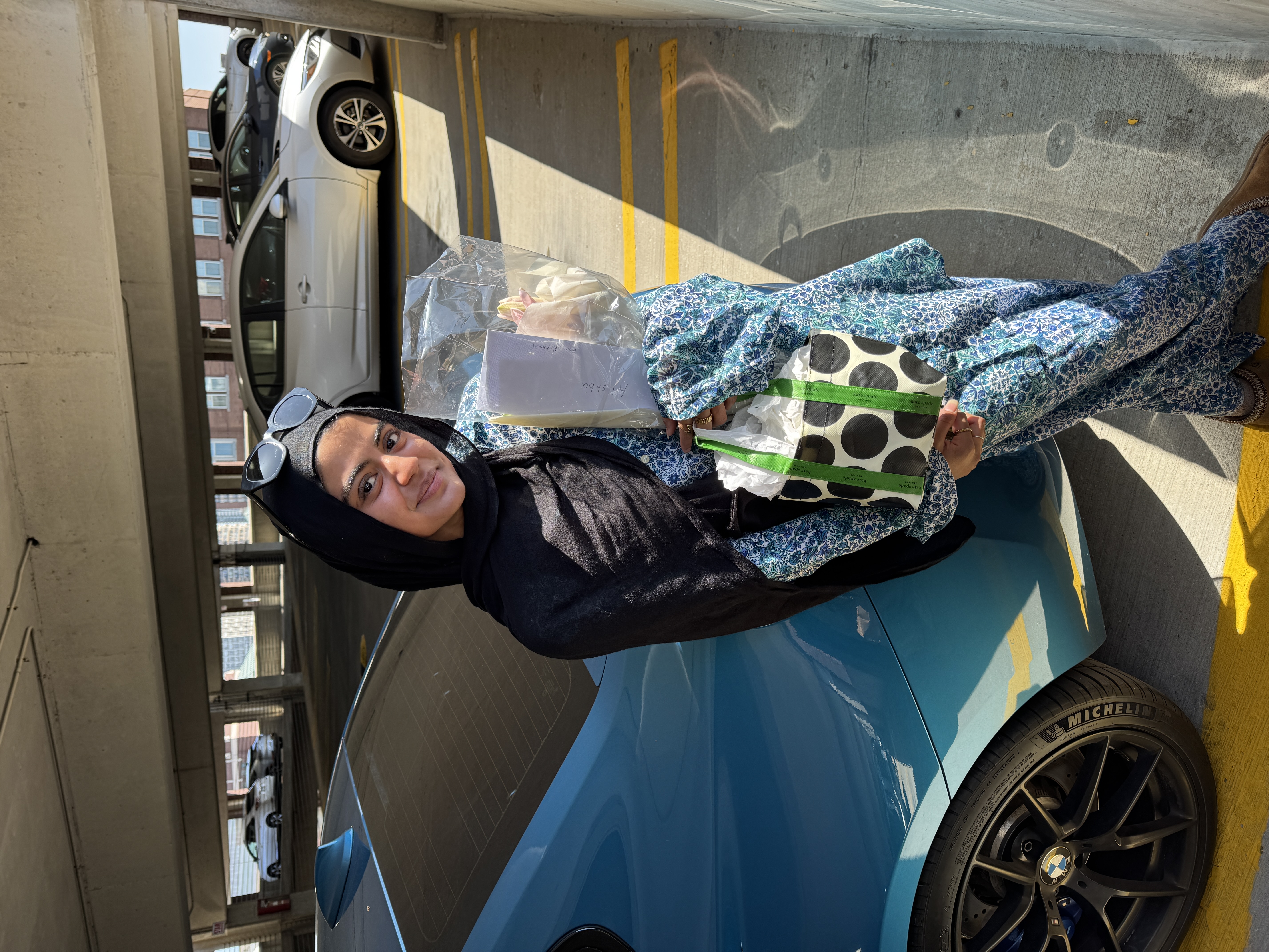 Alishba holding flowers by blue BMW